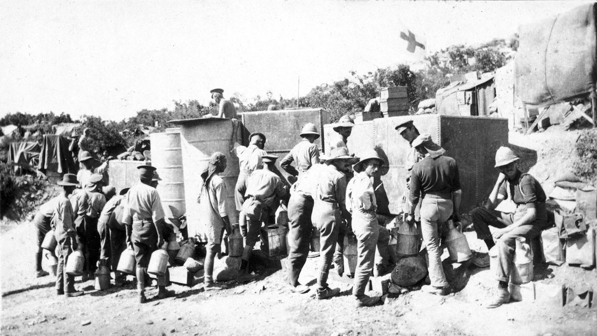 Soldiers carrying large cans standing beside water tanks at the foot of Walker's Ridge, July 1915.